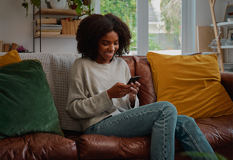 Woman on couch scrolling through her phone